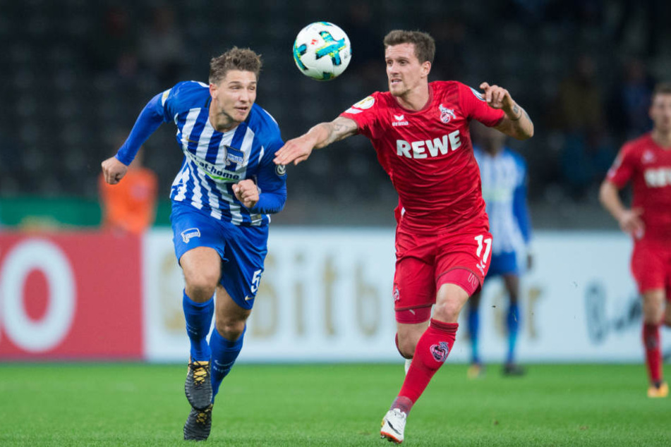 Berlins Niklas Stark (l) und Kölns Simon Zoller laufen zusammen zum Ball.