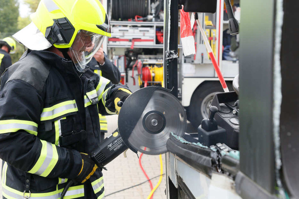 Die Feuerwehr zerlegt den Bus mit einem Trennschleifer, um einen Eingeklemmten zu bergen.