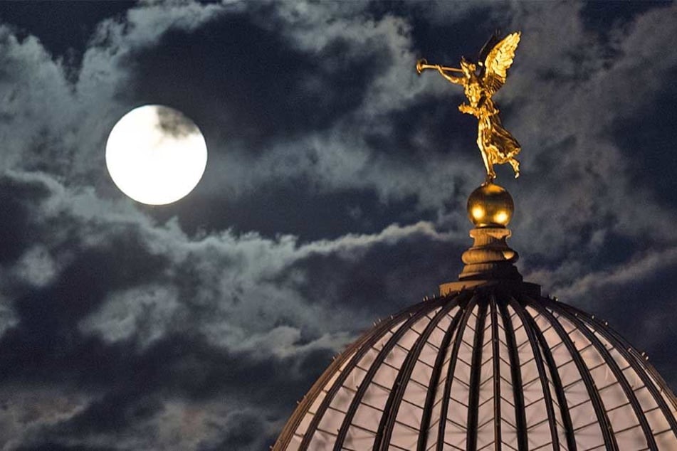 Der aufgehende Mond ist am 05.09.2017 neben der vergoldeten Figur des Posaunenengels Fama auf dem Dach der Kunstakademie in Dresden zu sehen.