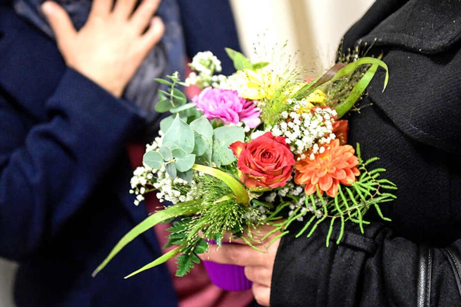 Angehörige warten mit Blumen in den Händen auf den Prozessbeginn.