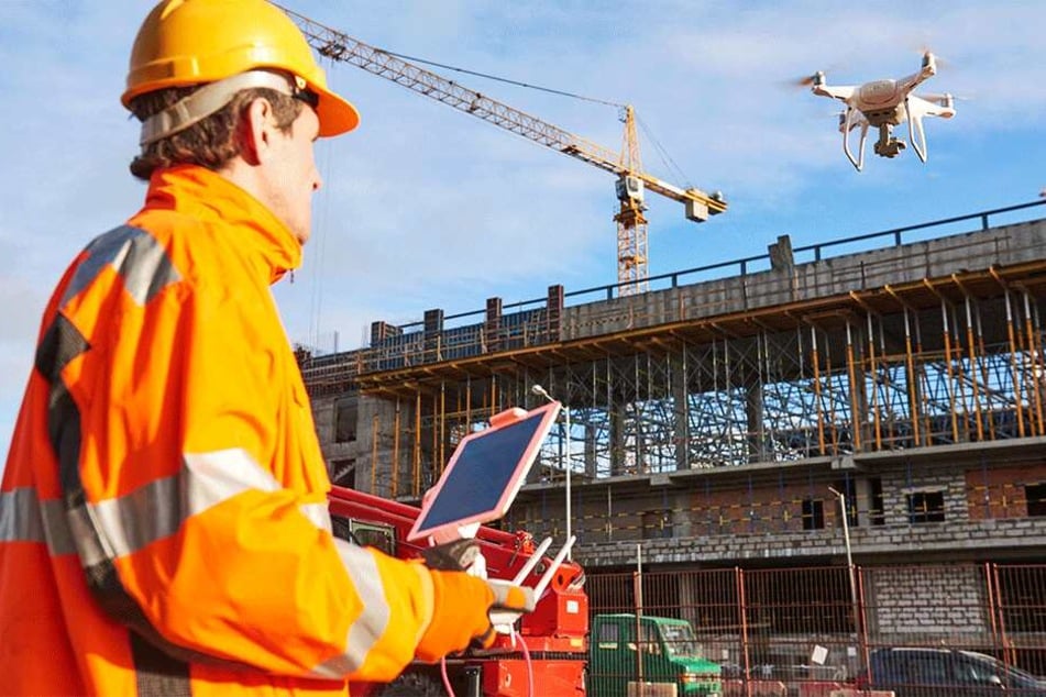 Ein Ingenieur nutzt eine Drohne als fliegendes Auge bei der Inspektion einer Baustelle. Die Technik kommt in der Wirtschaft immer häufiger zum Einsatz.