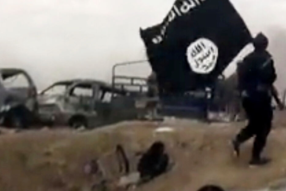 Das Archivbild zeigt einen Anhänger des Islamischen Staats mit einer Fahne der Organisation.