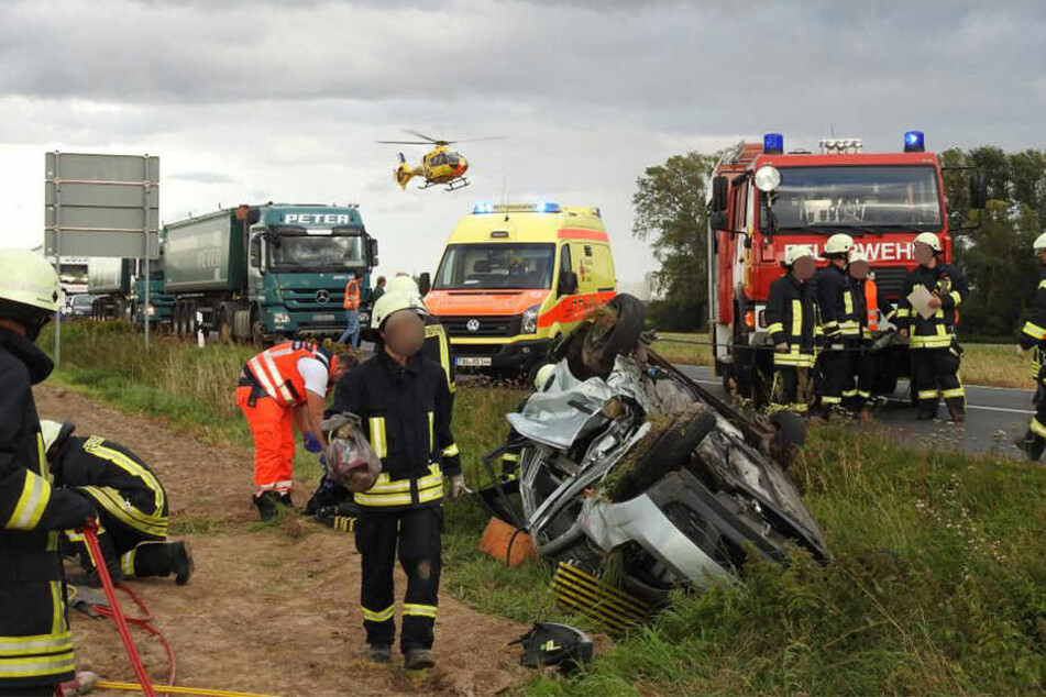 Die Kameraden stehen mitgenommen neben den verunglückten Autos. Im Hintergrund hebt ein Hubschrauber ab.