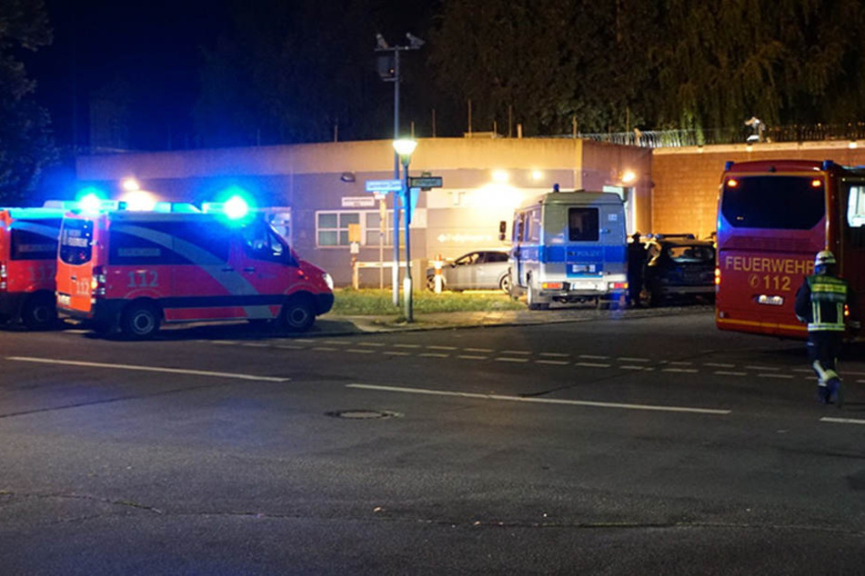 Mehrere Einsatzwagen der Feuerwehr und Polizei stehen vor dem Tor 1 der Justizvollzugsanstalt Plötzensee.