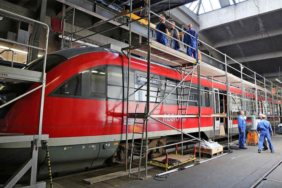 Mitarbeiter der Erzgebirgsbahn montieren Zusatzaggregate auf das Dach eines Triebwagens der Baureihe 642.