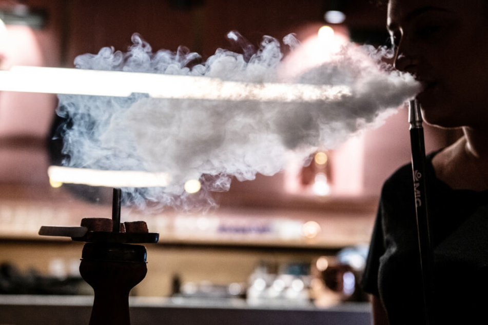 Eine junge Frau lässt Shisha-Rauch aus ihrem Mund entweichen (Symbolfoto).
