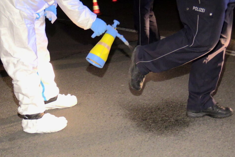 Ein Feuerwehrmann desinfiziert die Schuhe eines Polizisten.
