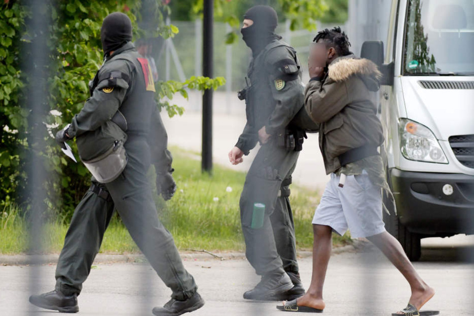 In der Landeserstaufnahmeeinrichtung für Flüchtlinge (LEA) wird ein Mann von maskierten Polizisten eskortiert. (Archivbild)