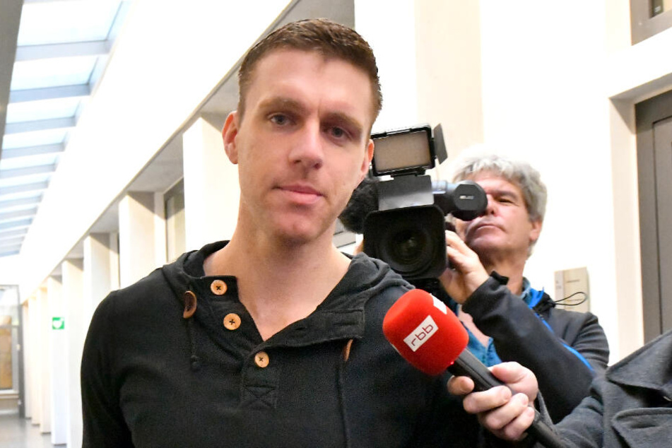 Der ehemalige NPD-Politiker Maik Schneider geht im Gericht an einem Fernsehteam vorbei.