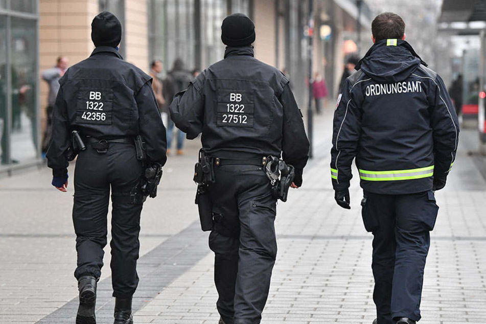 Ein Mitarbeiter des Ordnungsamtes und zwei Beamte der Bereitschaftspolizei gehen auf Streife vor dem Einkaufszentrum Blechen-Carré