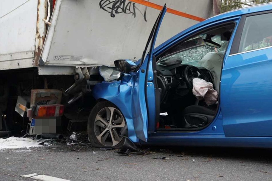Das Auto steckt mit der kompletten Front unter dem Laster.