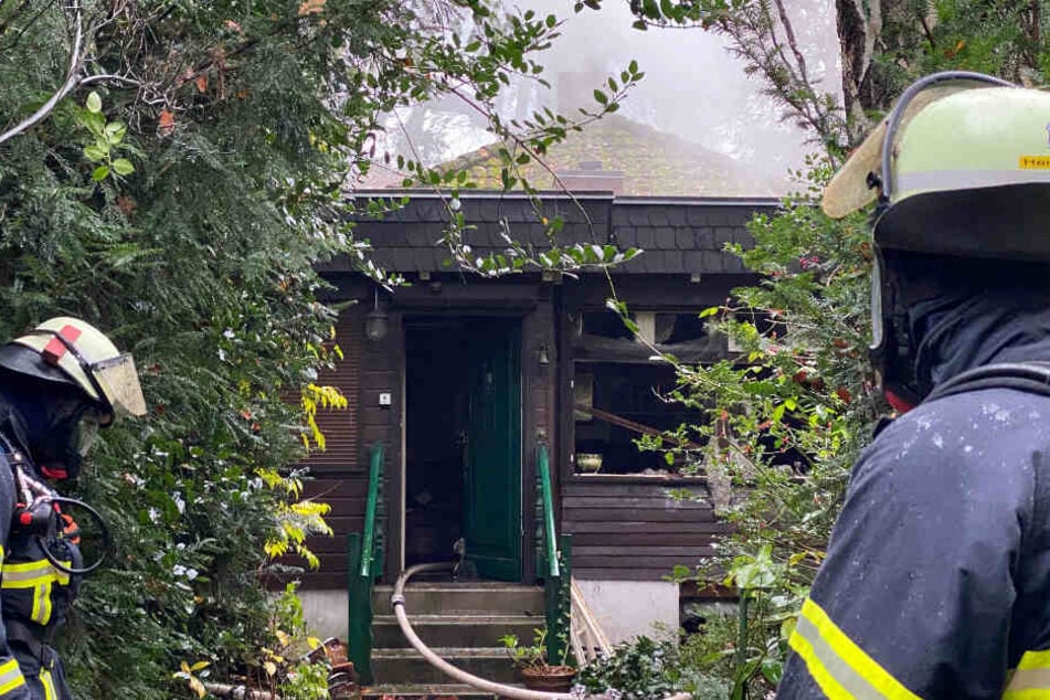 Feuerwehrkräfte stehen vor dem brennenden Haus.