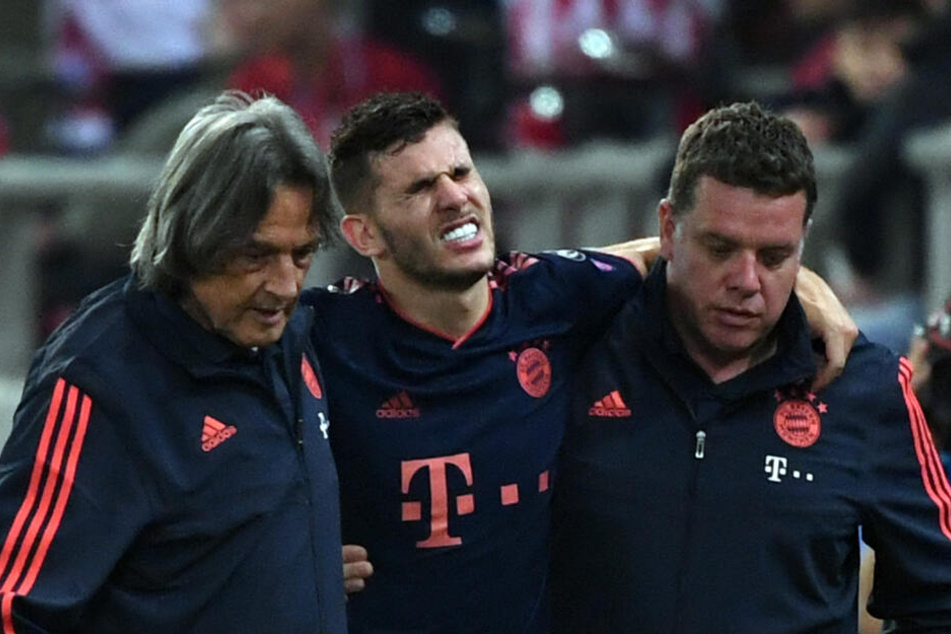 Lucas Hernandez (M.) wird mit schmerzverzerrtem Gesicht vom Platz geführt.