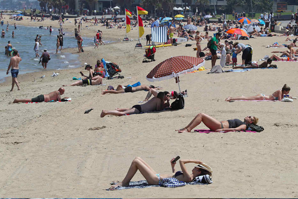 Strandbesucher liegen am Jahresende am Strand von St. Kilda in Melbourne.