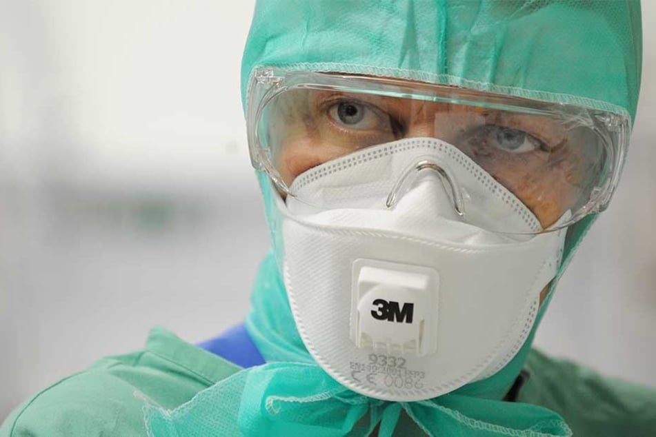Zur Vermeidung einer Virus-Infektion trägt eine Schwester Schutzkleidung und Schutzmaske.