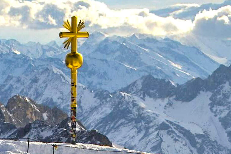 Das Foto aus einer Webcam zeigt das beschädigte Gipfelkreuz der Zugspitze, an dem rechts unten einige vergoldete Strahlen abgebrochen sind.