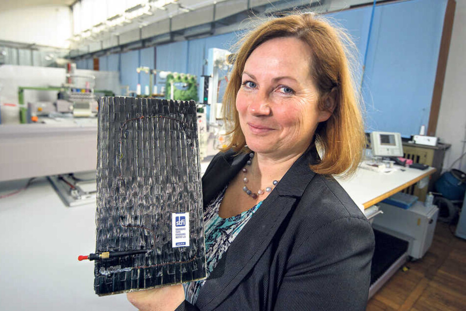 Elke Thiele vom STFI zeigt ein Betonteil mit der Überwachungs-Glasfaser, die
in einer Steckverbindung für Messgeräte endet.