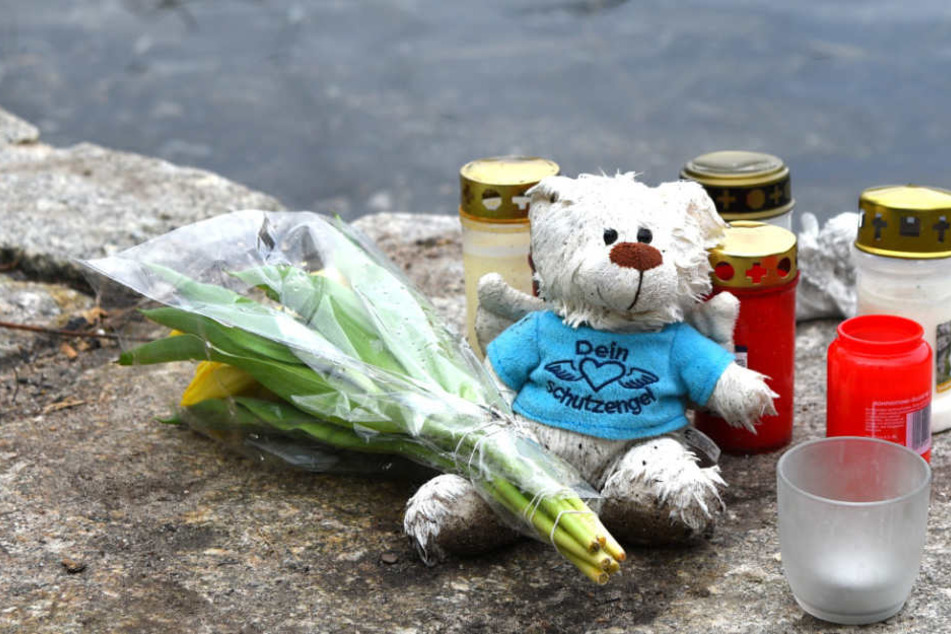 Blumen, Kerzen und ein Plüschtier liegen an einem Weiher in der Nähe des Fundortes einer Babyleiche. (Archivbild)