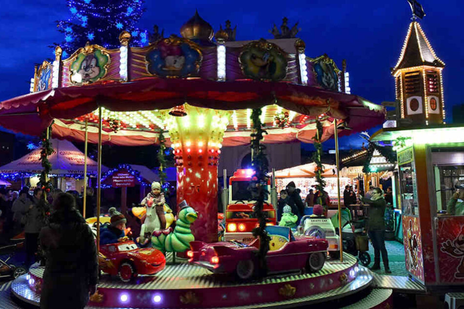 Ein Kinderkarussell dreht sich am 21.11.2016 in Potsdam (Brandenburg) vor der blau beleuchteten Tanne auf dem Weihnachtsmarkt.