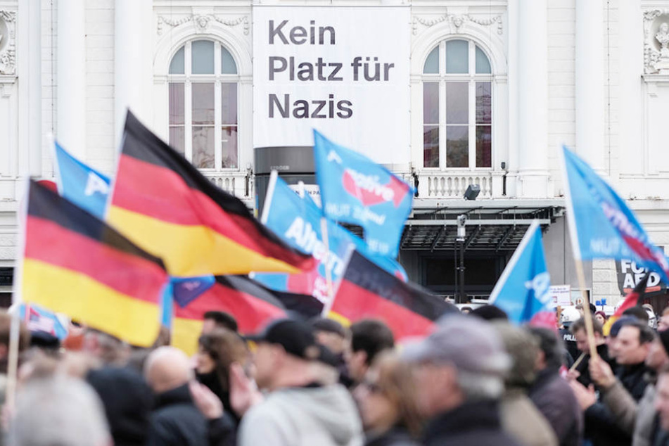 Teilnehmer einer AfD-Demo schwenken am in Hamburg Fahnen vor dem Deutschen Schauspielhaus von dem ein Plakat mit der Aufschrift "Kein Platz für Nazis" herunter hängt. (Symbolbild)