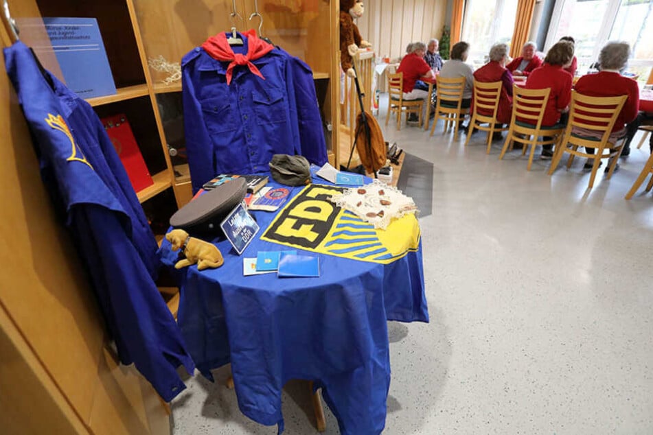 Bei einem "Museumstag" im DRK-Seniorenheim in Teterow hängen und liegen Pionier-Blusen, FDJ-Blusen, FDJ-Fahnen und andere DDR-Utensilien auf einem Tisch im Raum.