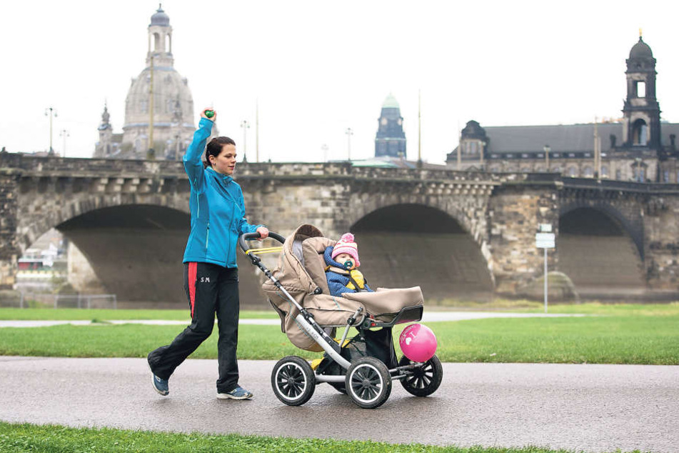 Linke Hand am Kinderwagen, rechter Arm in der Luft: Silke Meißner (30) mit
Tochter Lea (14 Monate) bei einer Übung zum Aufwärmen.