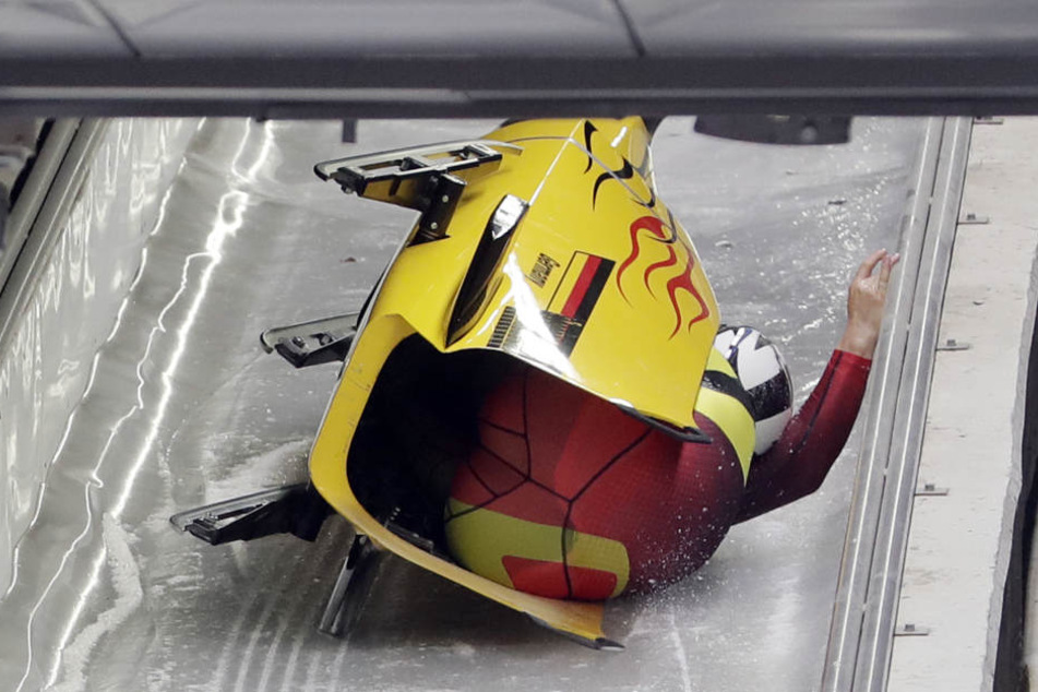 Pilot Nico Walther und Anschieber Christian Poser aus Deutschland rutschen nach einem Sturz auf der Seite den Eiskanal hinunter.