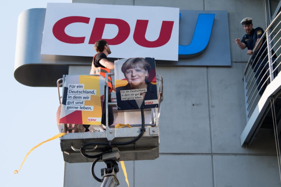 Ein Demonstrant bringt das CDU-Logo mit einer Hebebühne an der CSU-Zentrale an.