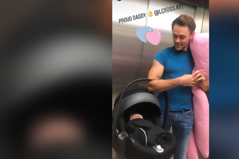 Stolzer Papa: Liam Cross trägt seine kleine Tochter in einer Babyschale.