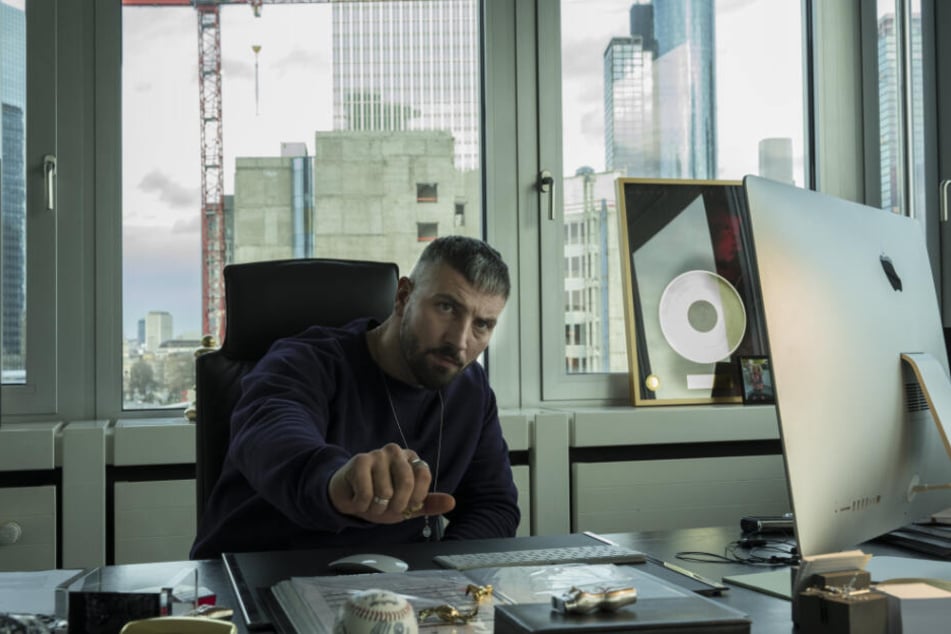 Murathan Muslu als Plattenboss Kalifa sitzt in seinem Büro.