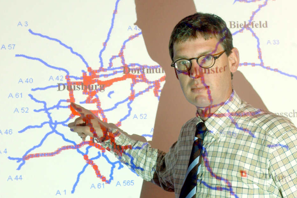Stauforscher Michael Schreckenberg vor einer Projektion, die Messpunkte auf den nordrhein-westfälischen Autobahnen zeigt.