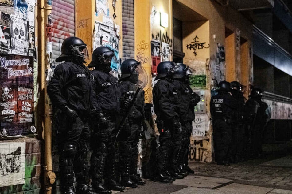 Polizeibeamte stehen bei einer Razzia in der Rigaer Straße in Berlin-Friedrichshain vor einem Haus. (Symbolbild/Archivbild)
