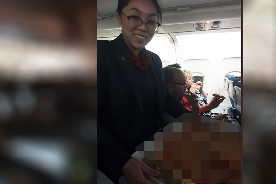 Eine Stewardess verteilt die Pizza, die der Pilot für seine Passagiere bestellt hatte.