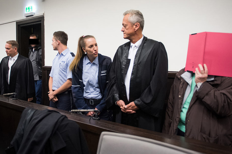 Angelika W. hält sich bei Prozessbeginn eine rote Akte vor das Gesicht.