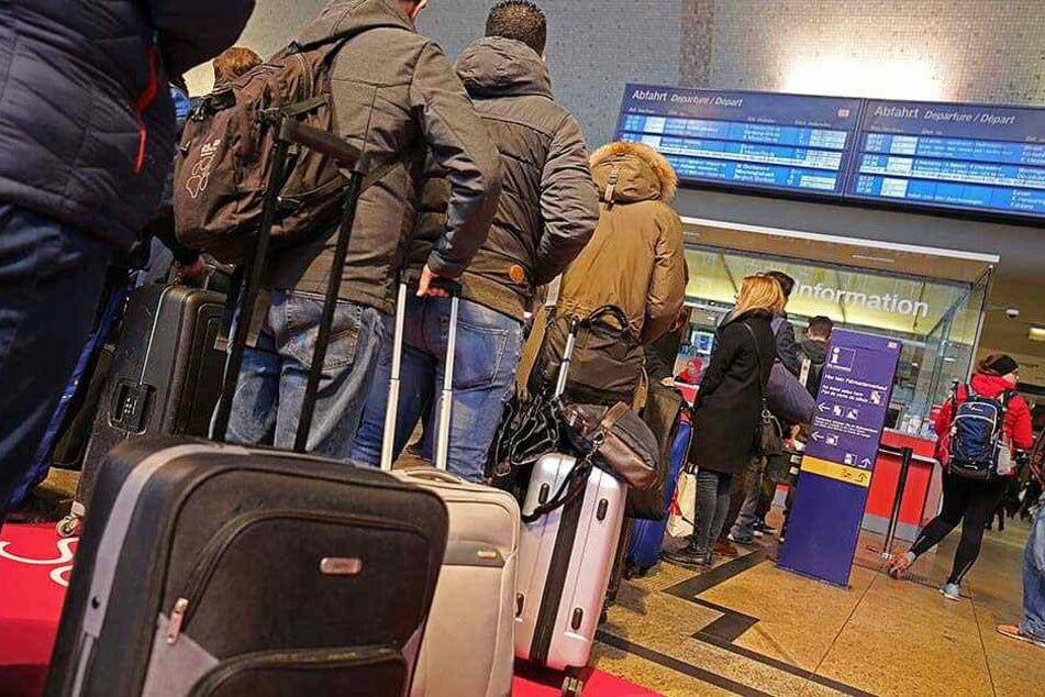Bahnreisende stehen im Kölner Hauptbahnhof und informieren sich, wie und wo sie die Nacht verbringen können