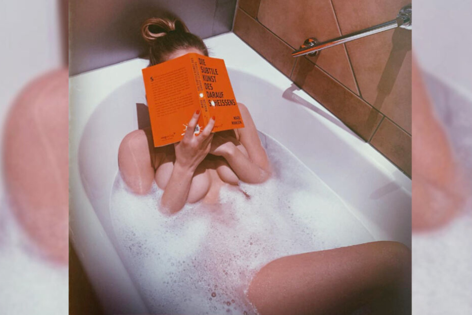 Playmate Annetta Negare liegt nackt in der Badewanne und verdeckt ihr Gesicht mit einem Buch.