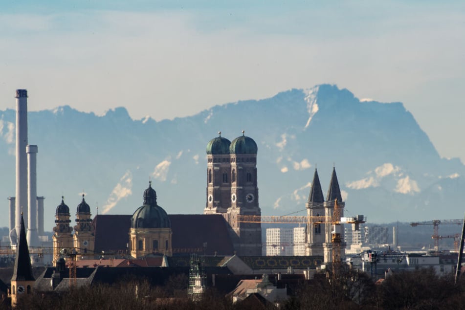 Die Skyline der bayerischen Landeshauptstadt ist vor der Kulisse der etwa 90 Kilometer entfernten Alpen mit der Zugspitze (rechte Bildhälfte) zu sehen.