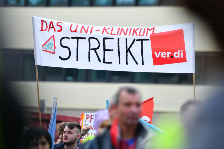Teilnehmer halten bei einer Kundgebung vor dem Neubau der Chirurgie des Universitätsklinikums ein Transparent mit der Aufschrift "Das Uni-Klinikum streikt" in die Höhe.