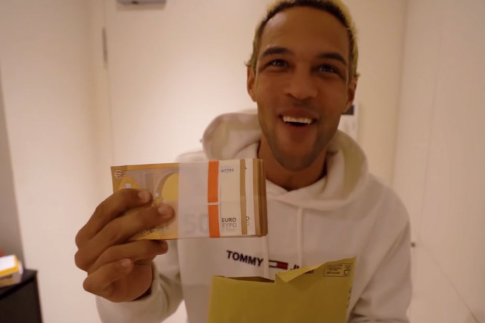 Simon Desue nimmt den Umschlag mit dem Falschgeld in Empfang.