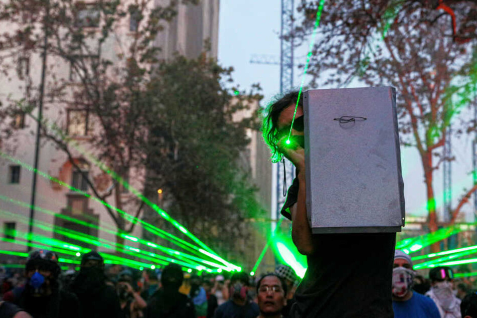 Demonstranten zielen bei einer Demonstration mit Laserpointern auf die Polizei.