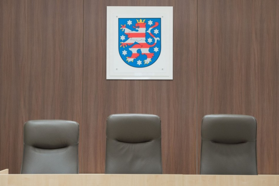 Drei Stühle stehen im Landgericht in Gera (Thüringen) vor dem Landeswappen.