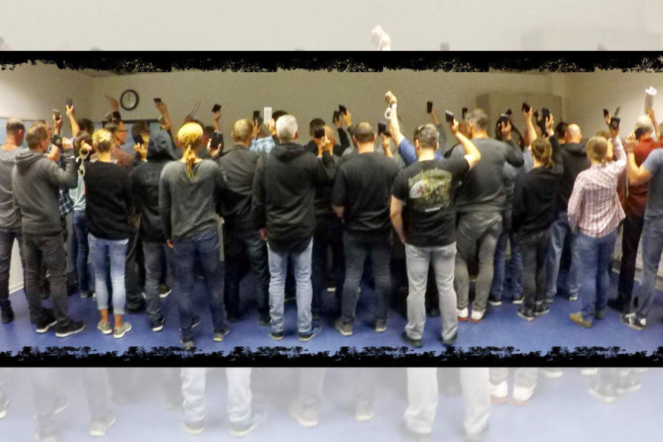 Handschellen, Smartphones und eine Zeitung halten die eingesetzten Ermittler beim gemeinsamen Rücken-Gruppenfoto hoch.