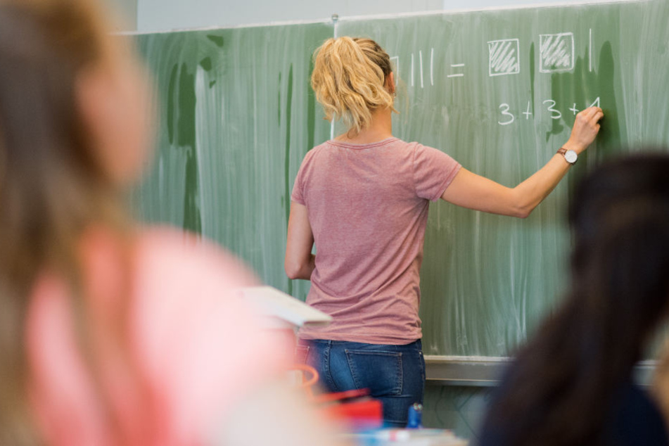 Eine junge Lehrerin schreibt an eine Schultafel im Mathematikunterricht einer 8. Klasse an einer Integrierten Gesamtschule.