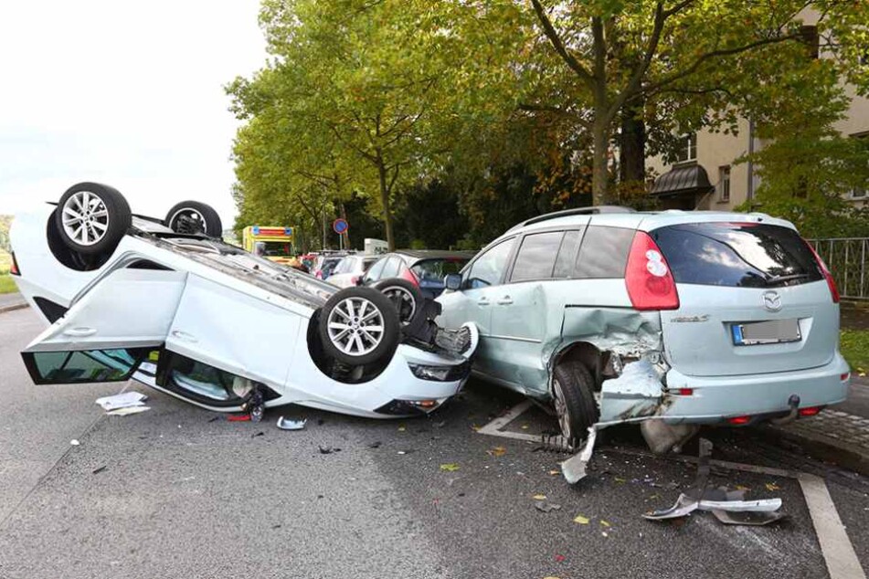 Der Skoda liegt auf dem Dach, deutlich erkennbar ist die schwere Beschädigung des Mazdas am linken Hinterradbereich.