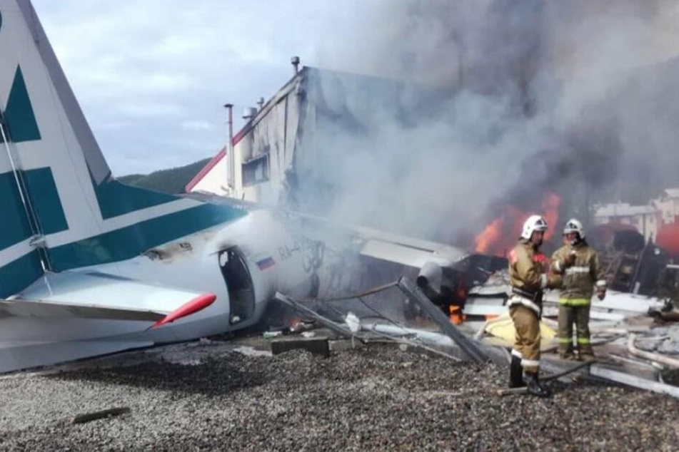 Feuerwehrleute löschen das brennende Flugzeug.