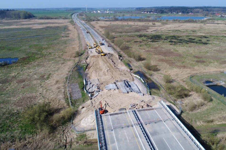 Bagger arbeiten am Rückbau des Straßendammes an dem zerstörten Teilstück der Autobahn A20.