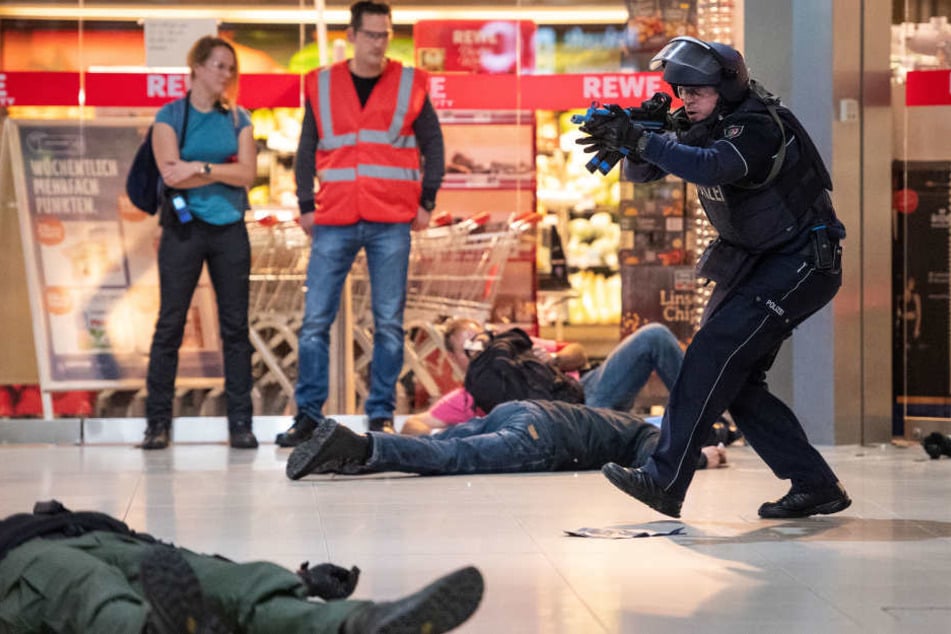 Polizisten gehen während einer Anti-Terror-Übung am Flughafen Köln/Bonn gegen angenommene Terroristen vor. Im Hintergrund stehen Beobachter der Übung.
