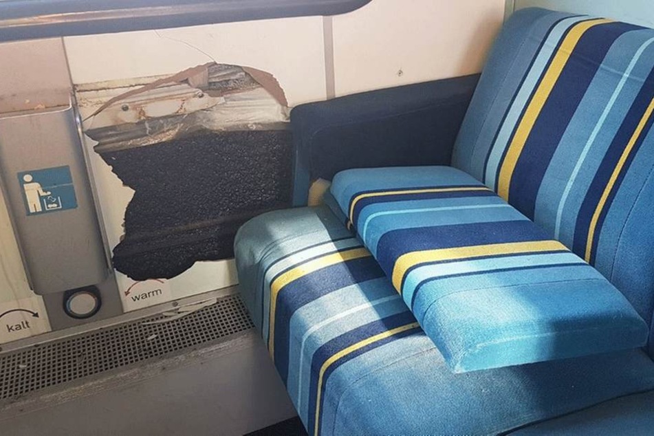 In der Wandverkleidung wurde diese Loch getreten, auf der Sitzbank liegt eine abgerissene Rückenlehne.