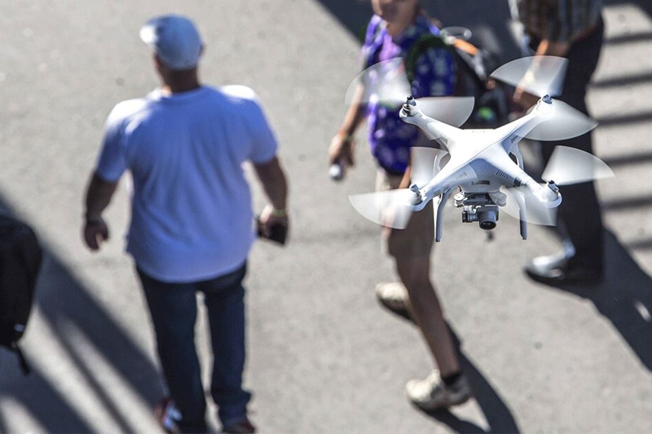 Eine Drohne fliegt über Menschen in der Stadt. So manchem ist diese Technik ein Dorn im Auge.