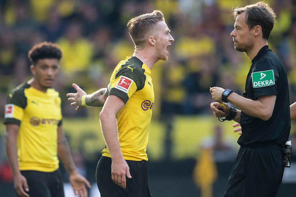 BVB-Kapitän Marco Reus (M.) diskutierte viel mit Schiedsrichter Markus Schmidt (r.) und bekam wegen seiner anhaltenden Meckerei auch die Gelbe Karte.